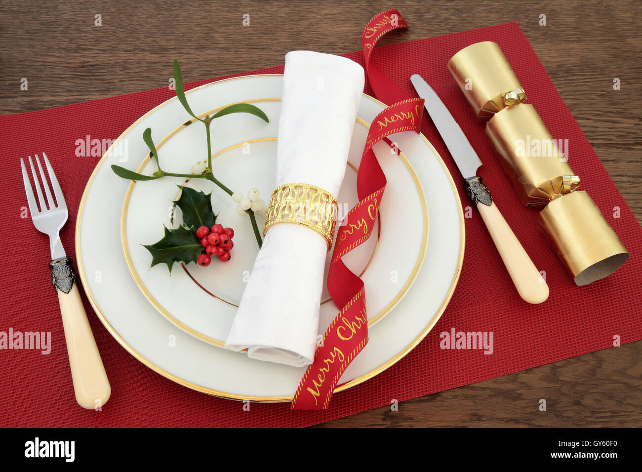 Cena di Natale messa in tavola con le piastre bianche, il coltello e la  forchetta, tovagliolo, nastro rosso, agrifoglio, vischio e cracker Foto  stock - Alamy