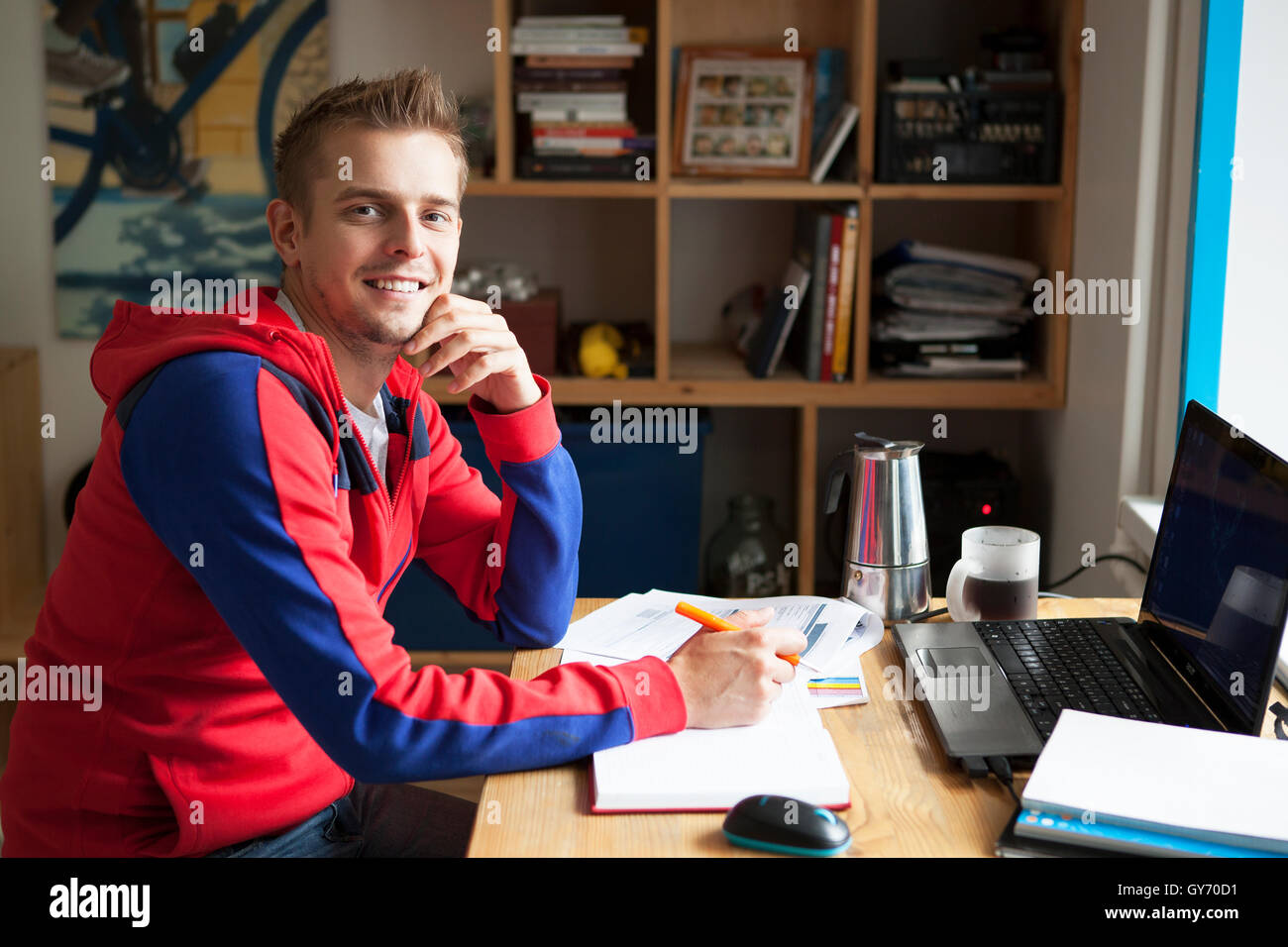 L'immagine orizzontale di un imprenditore scrivere appunti su un blocco di scrittura mentre è seduto alla sua scrivania dietro il suo nuovo notebook con il suo mattino Foto Stock