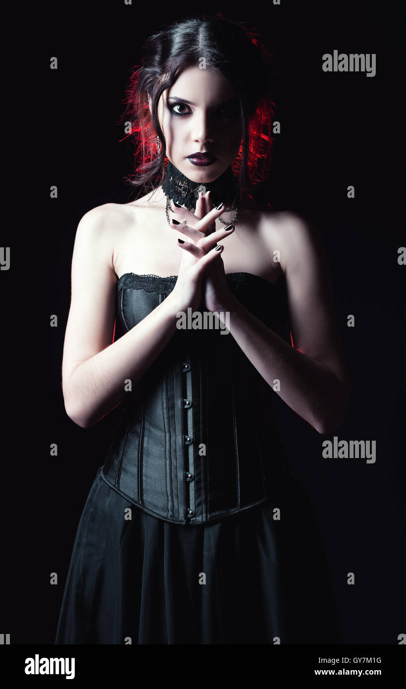 Drammatico ritratto di una bella donna di goth tra il buio Foto Stock