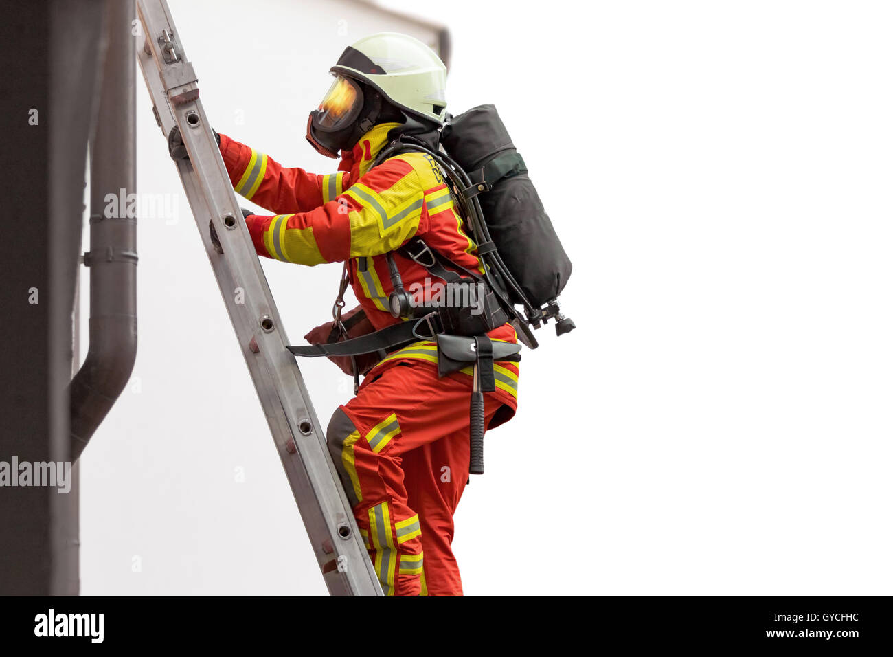 Fireman salendo una scala appoggiata su di un edificio Foto Stock