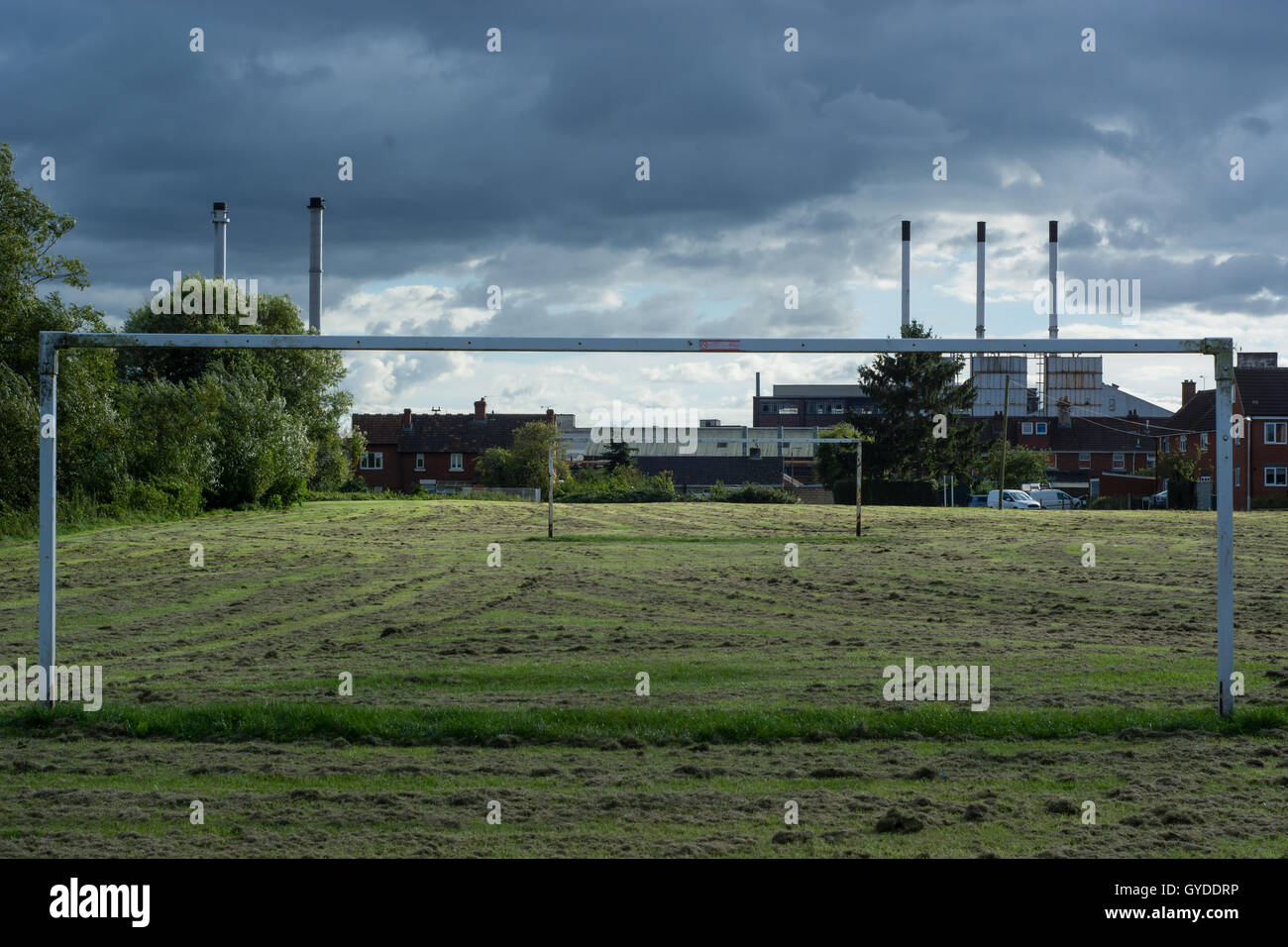 Campo da gioco, goalpost e camini in scena MelkshaIndustrial con pneumatici di fabbrica in città nel Wiltshire, Inghilterra, Regno Unito Foto Stock