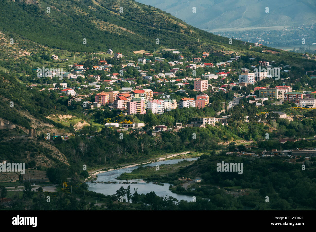 La vista panoramica di Mtskheta, Georgia. Uptown, zona residenziale sulla collina verde dal fiume di montagna in estate giornata di sole. Foto Stock