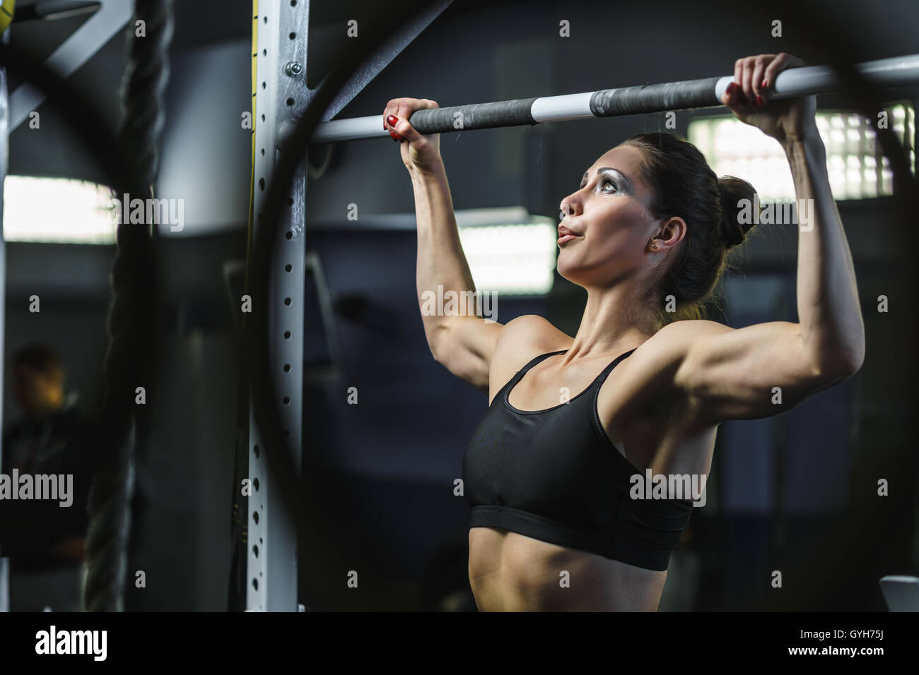Concetto: Potenza, forza, uno stile di vita sano, sport. Potente attraente donna muscolare CrossFit trainer fare tirare ups durante worko Foto Stock