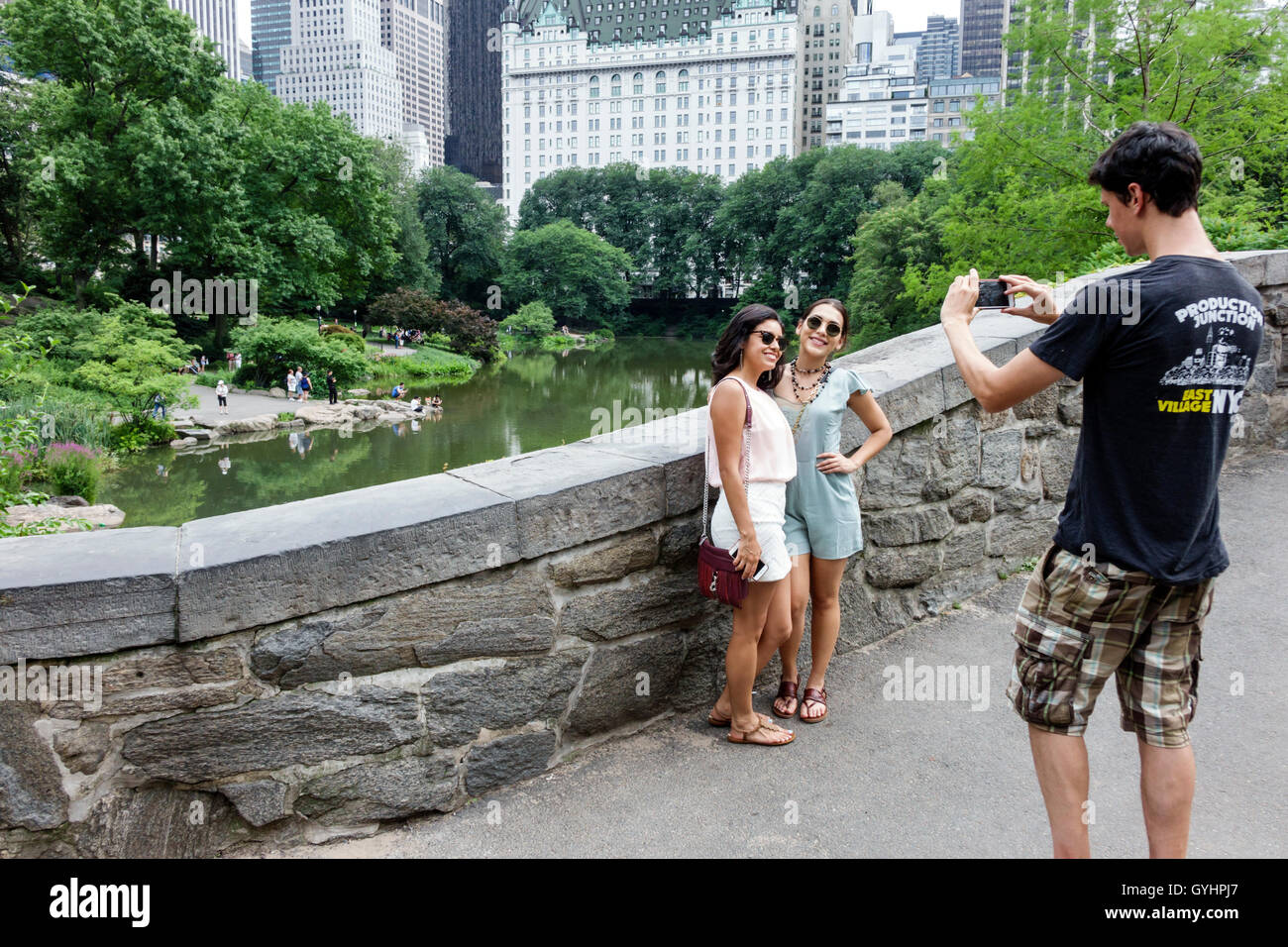New York City,NY NYC,Upper Manhattan,Central Park,Urban Park,The Pond,Water Body,paesaggistico,alberi,muro,adulti,uomo uomo maschio,donna donna donna femmina l Foto Stock