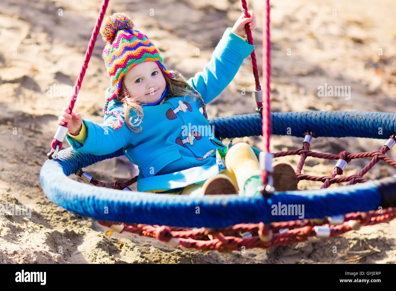 Bambina in caldo cappotto e hat su un parco giochi. Bambino che gioca all'aperto in autunno. Bambini giocano sul cortile della scuola Foto Stock