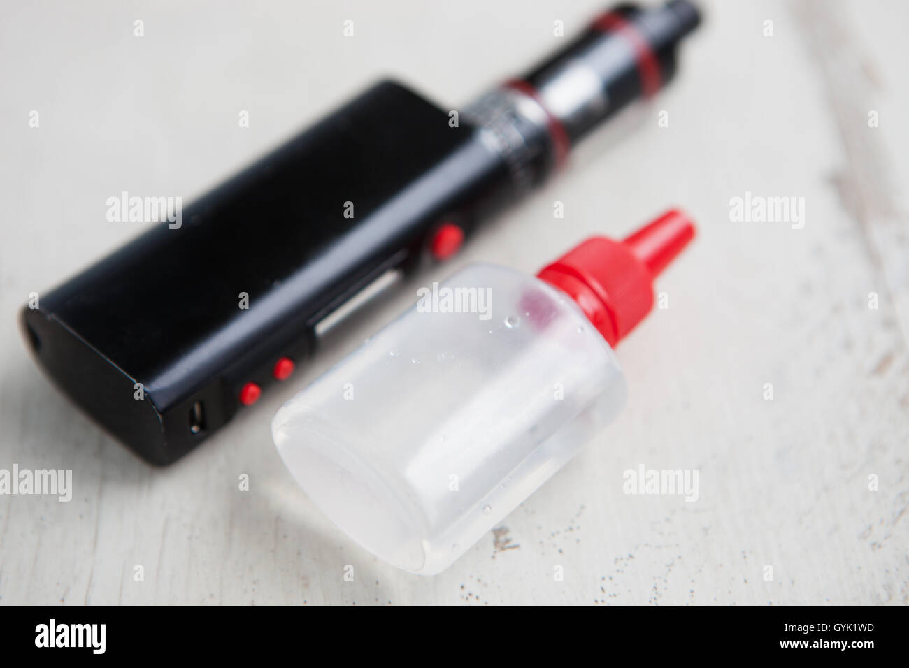 Vaporizzatore dispositivo per fumatori e contenitore in plastica con e-succhi di frutta.Riempire liquido tabacco con glicol glicole e glicerina base. Posizionare testo sulla bottiglia trasparente. Foto Stock