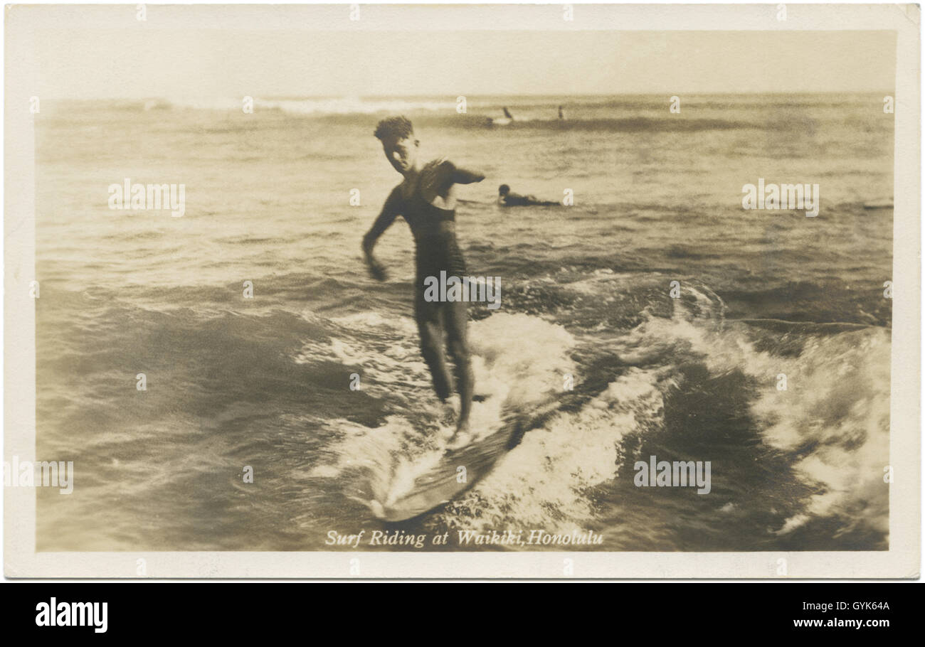 Surfer di equitazione con la tavola da surf in legno di Waikiki, Honolulu, Hawaii c1920s. Foto Stock