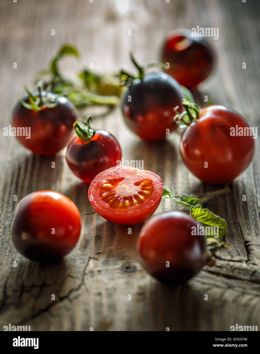 Succosa pomodori nero e sezioni sullo sfondo di legno Foto Stock