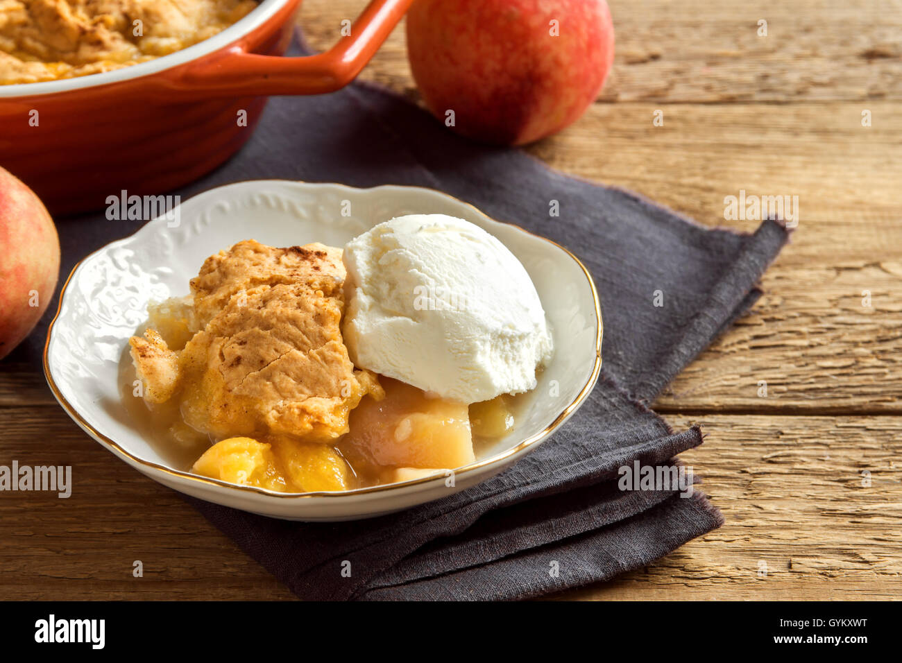 In casa peach cobbler con gelato alla vaniglia su legno rustico sfondo - sano dessert di pasticceria Foto Stock