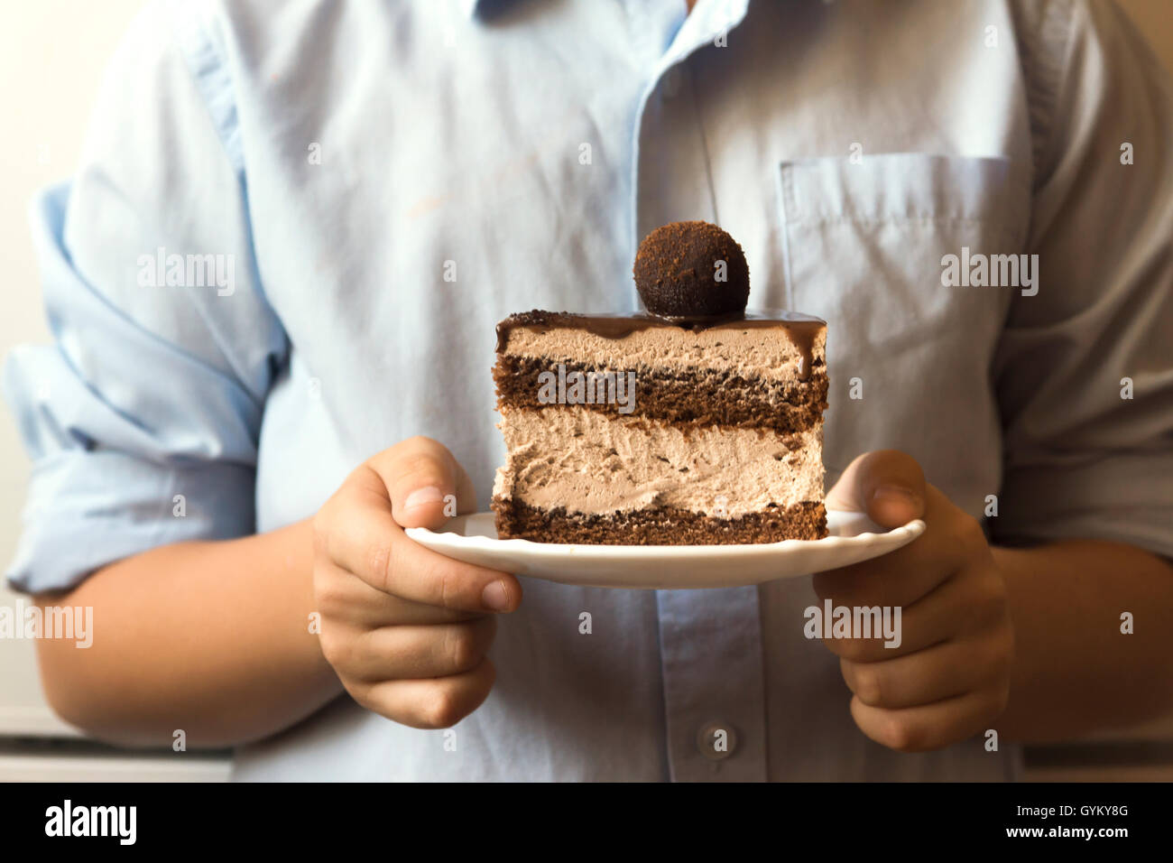 Closeup mani tenendo pezzo di torta al cioccolato in piastra bianca Foto Stock