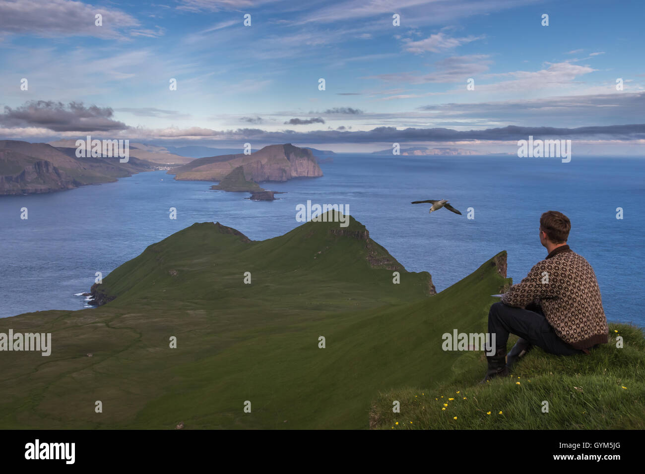 Un ragazzo delle isole Faeroeer seduto sulla cima dell'isola di Mykines, Isole Faerøer Foto Stock