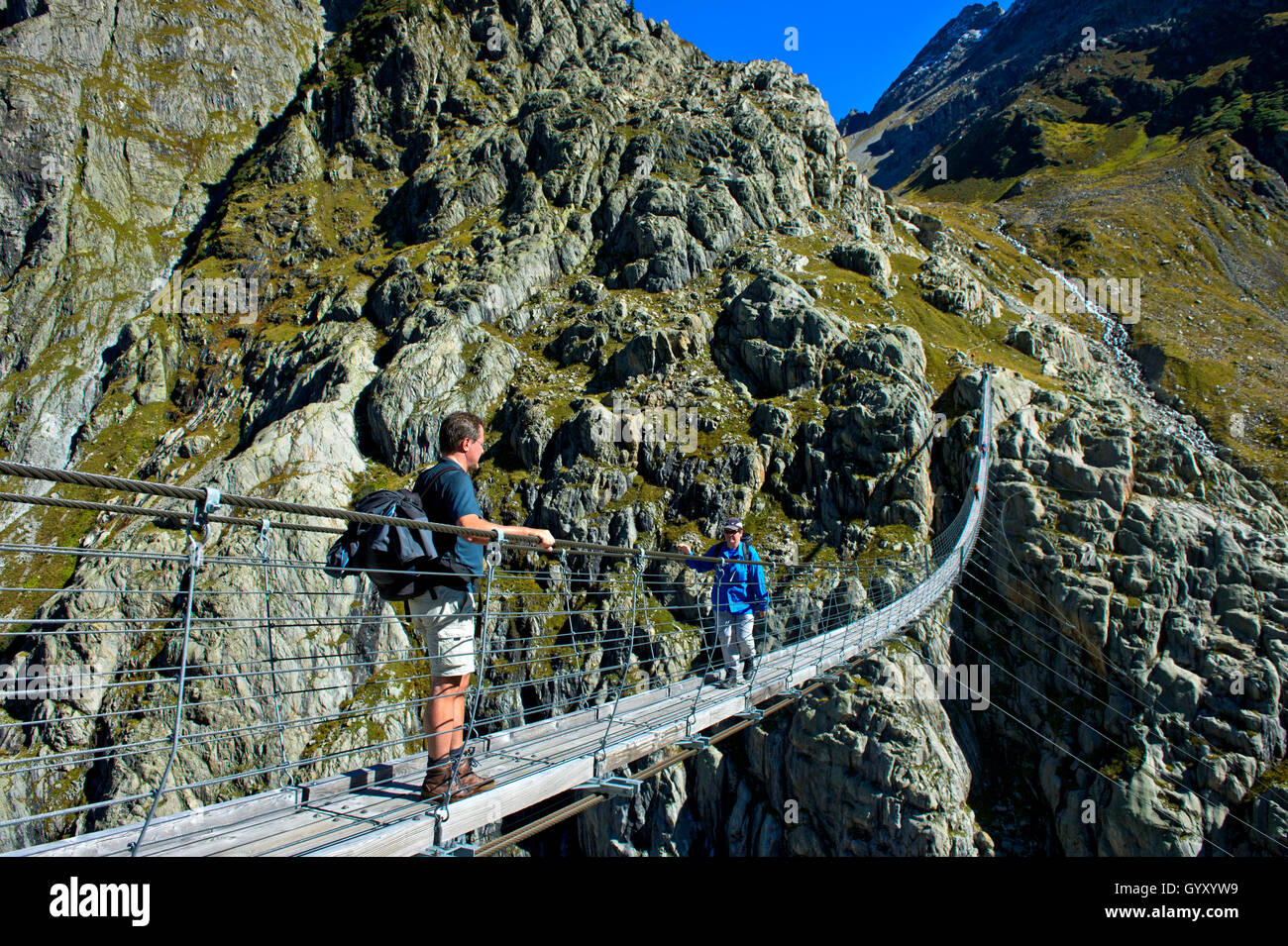 Gli escursionisti che attraversano la sospensione ponte bridgeTrift attraverso il Trift Gorge, Gadmen, cantone di Berna, Svizzera Foto Stock