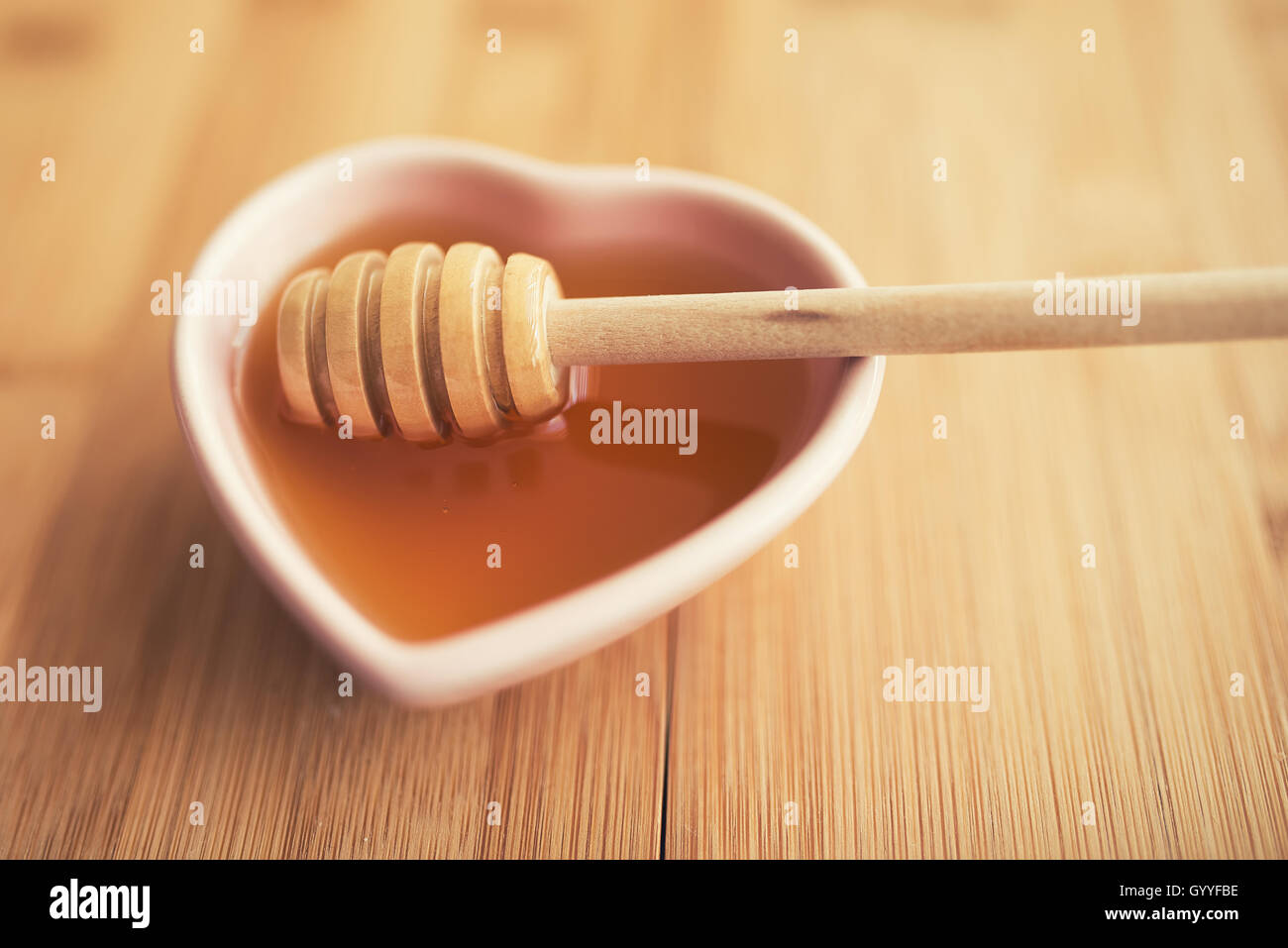 Naturali freschi di miele in un vasetto di miele bilanciere su un tavolo di legno Foto Stock