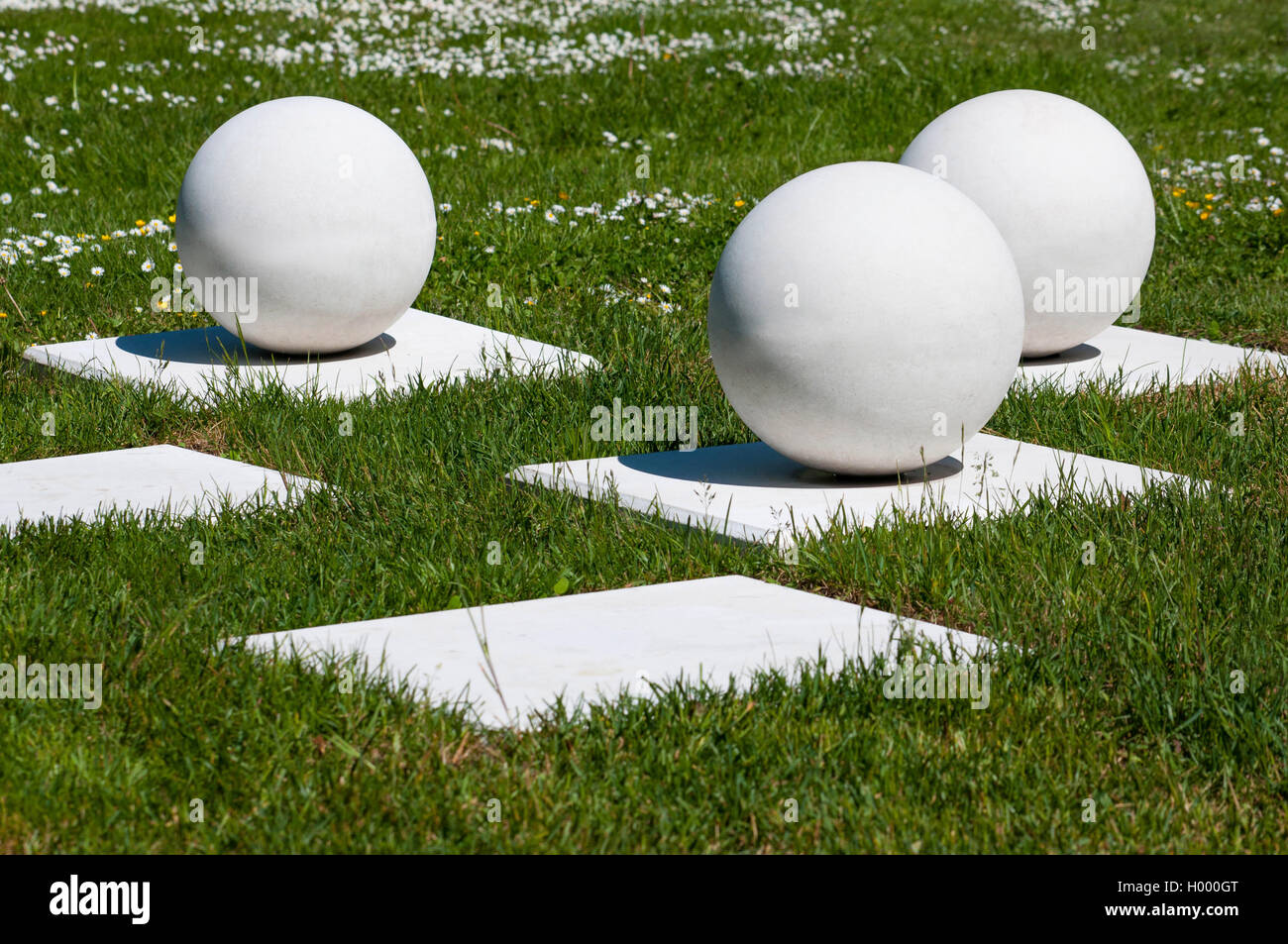 Abstract composizione esterna di bianco sfere stabile sulle basi in erba Foto Stock