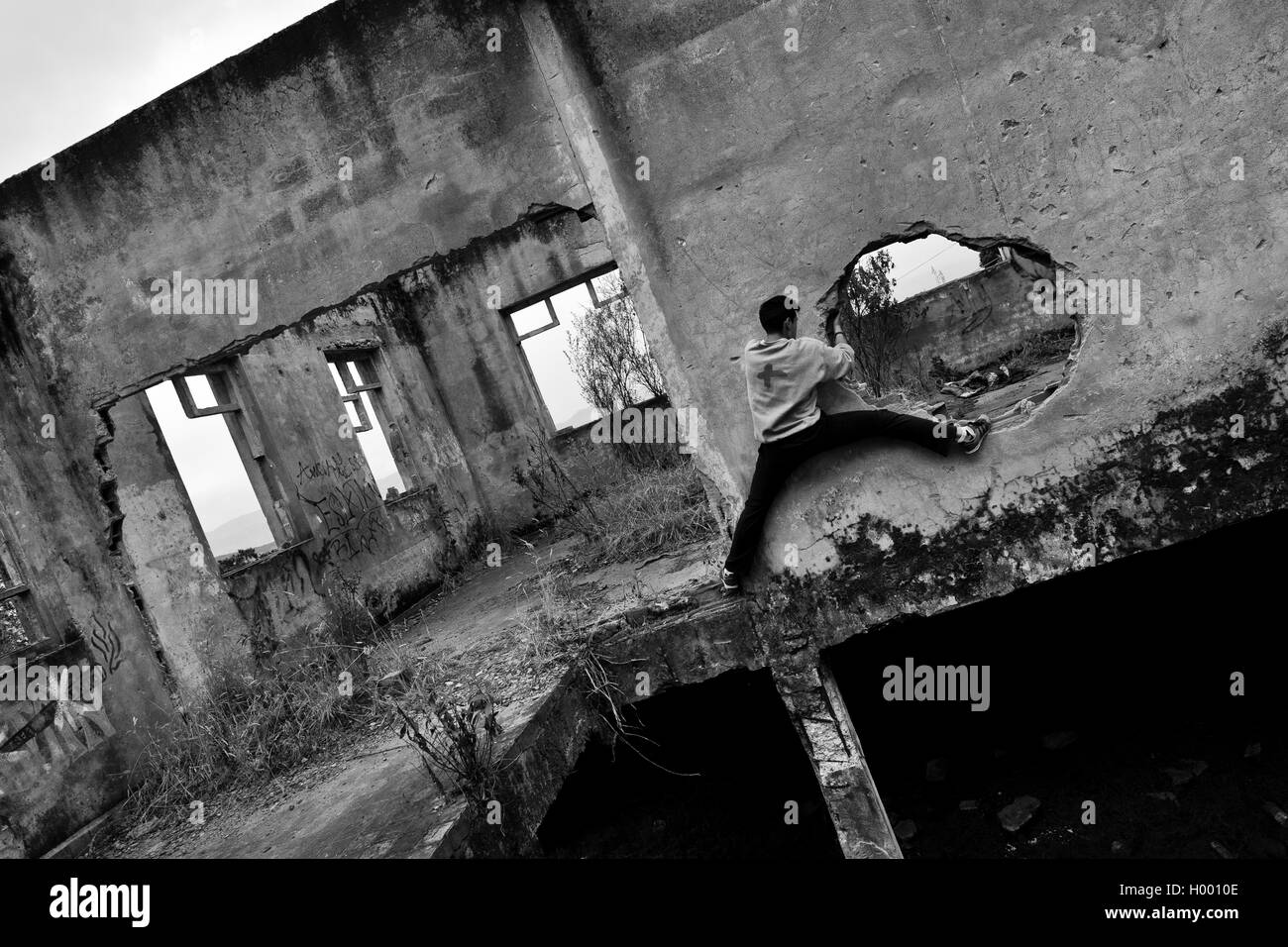 Un colombiano parkour runner salite all'interno di una casa in rovina durante una corsa libera sessione di formazione di Bogotá, in Colombia. Foto Stock