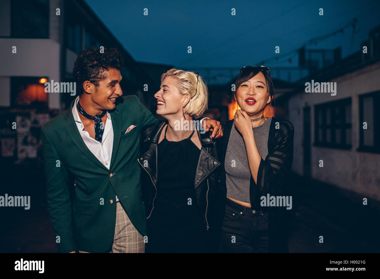 Diversi gruppi di amici di camminare sulla strada di notte. Multirazziale giovane uomo e donne godendo all aperto in serata. Foto Stock