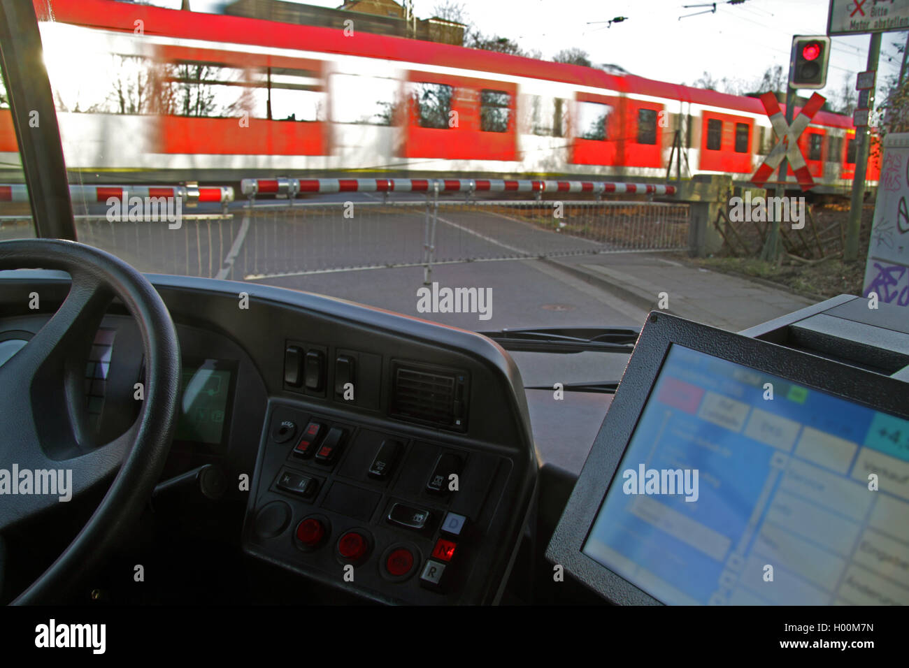 In attesa del bus di fronte a un attraversamento ferroviario, Germania Foto Stock