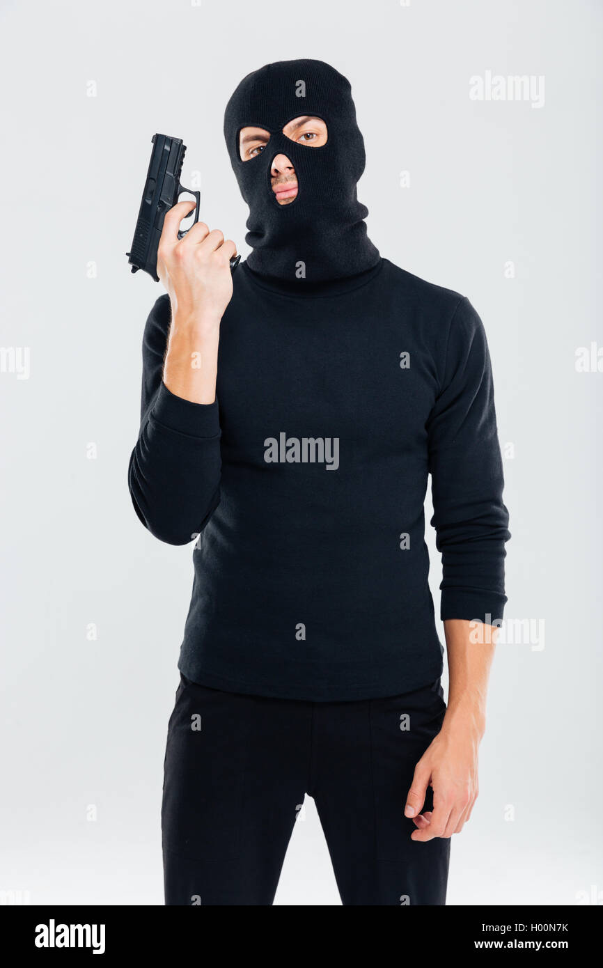 Uomo delinquente in passamontagna permanente e la pistola di contenimento  Foto stock - Alamy