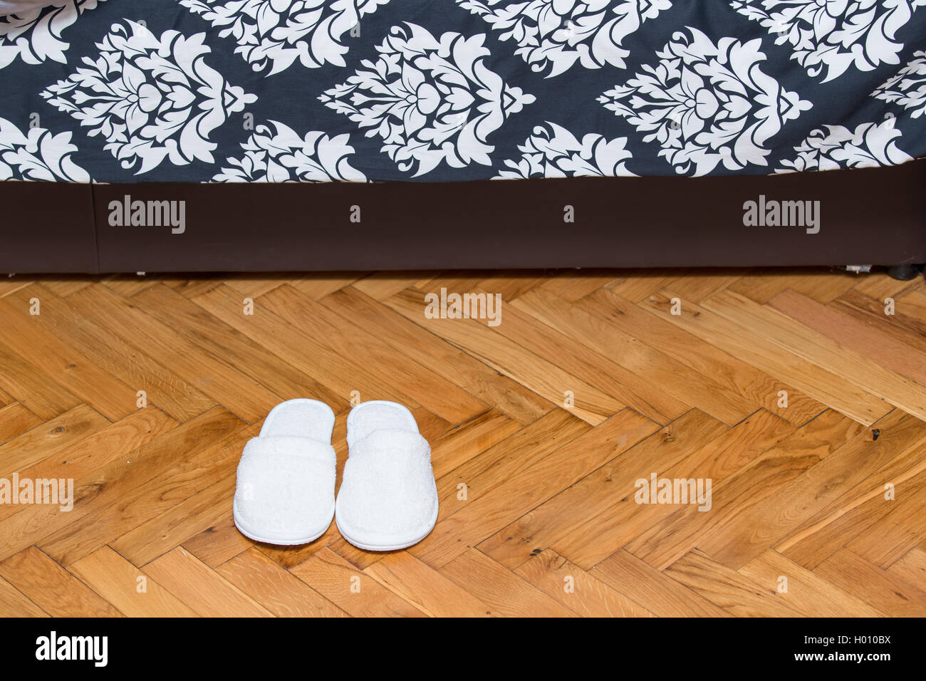 Pantofole sul pavimento in legno parquet davanti sul letto in casa Foto  stock - Alamy