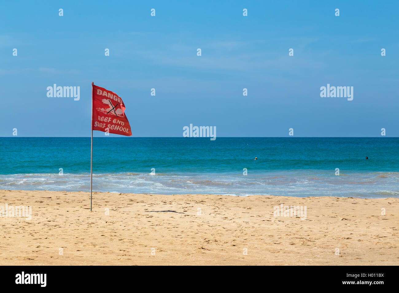 HIKKADUWA, SRI LANKA - 24 febbraio 2014: pericolo rosso bandiera sventolare nel vento sulla spiaggia sabbiosa. Hikkaduwa è ben noto giornat turistica Foto Stock