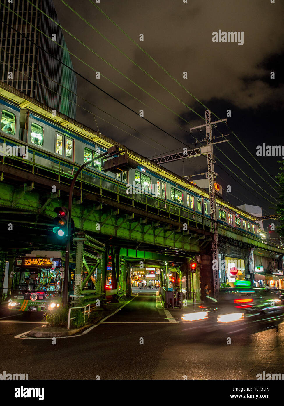 Una linea Yamanote treno passeggeri su ferrovia sopraelevata al di sopra di strade trafficate, una città giapponese di notte, Yurakucho, Tokyo, Giappone Foto Stock