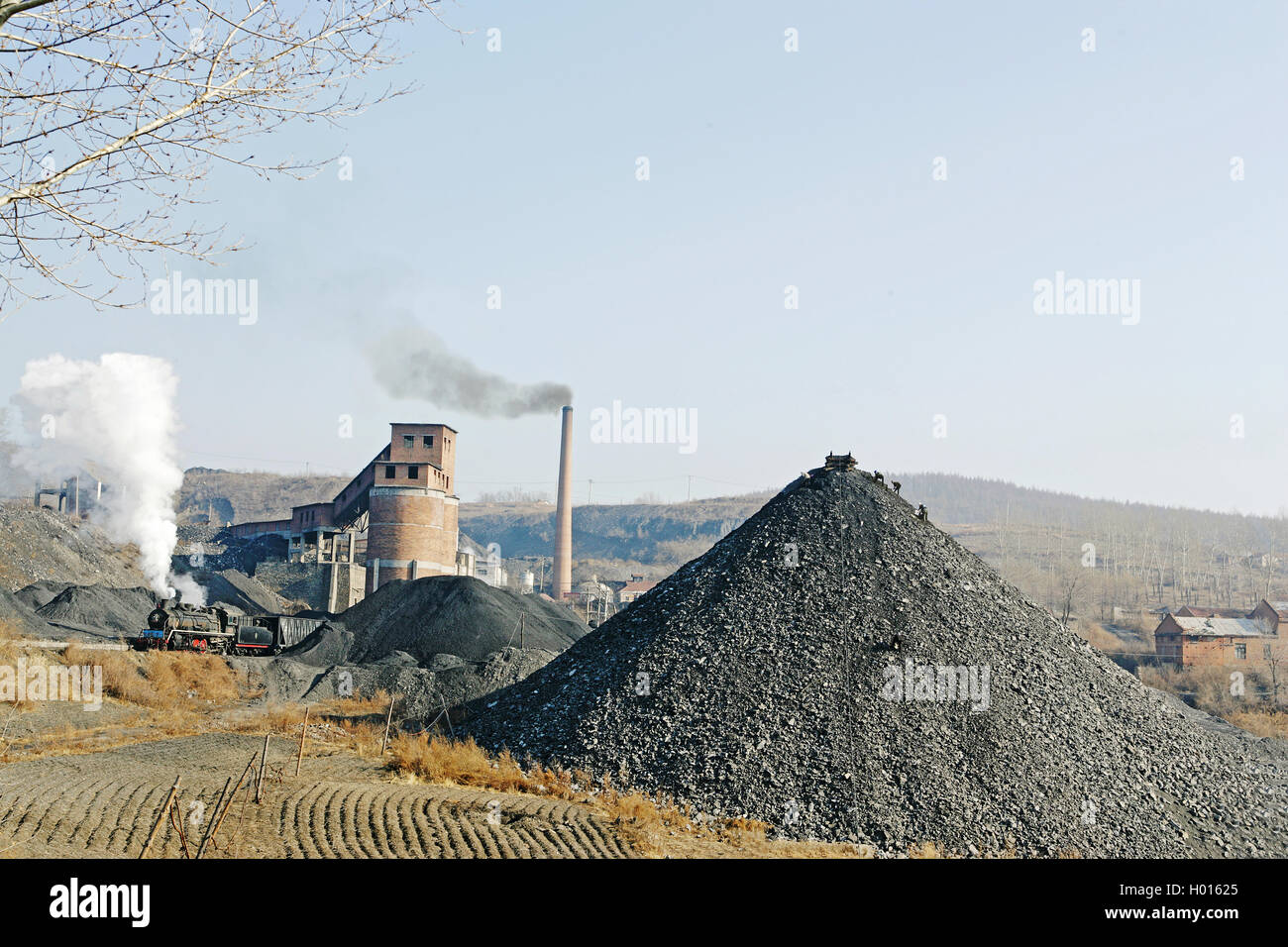 Un SY classe 2-8-2 tira bruscamente lontano da Qikeng Colliery con un rastrello caricato. "Scoria Masies" può essere visto spigolando i pezzi di carbone Foto Stock