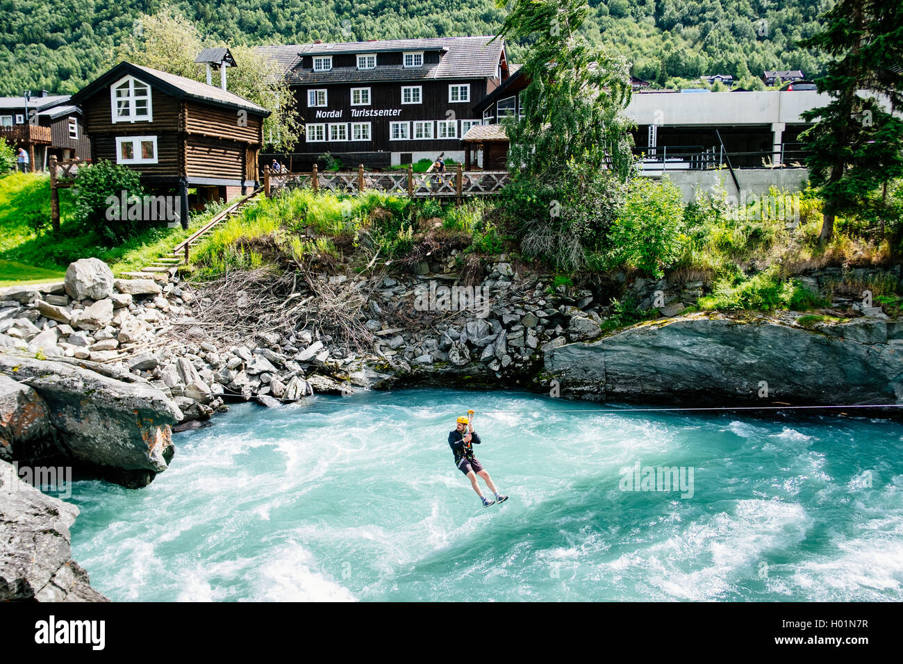 Un turista su una traversa tirolese oltre il fiume Bovra nella città di Lom, Oppland Norvegia Foto Stock