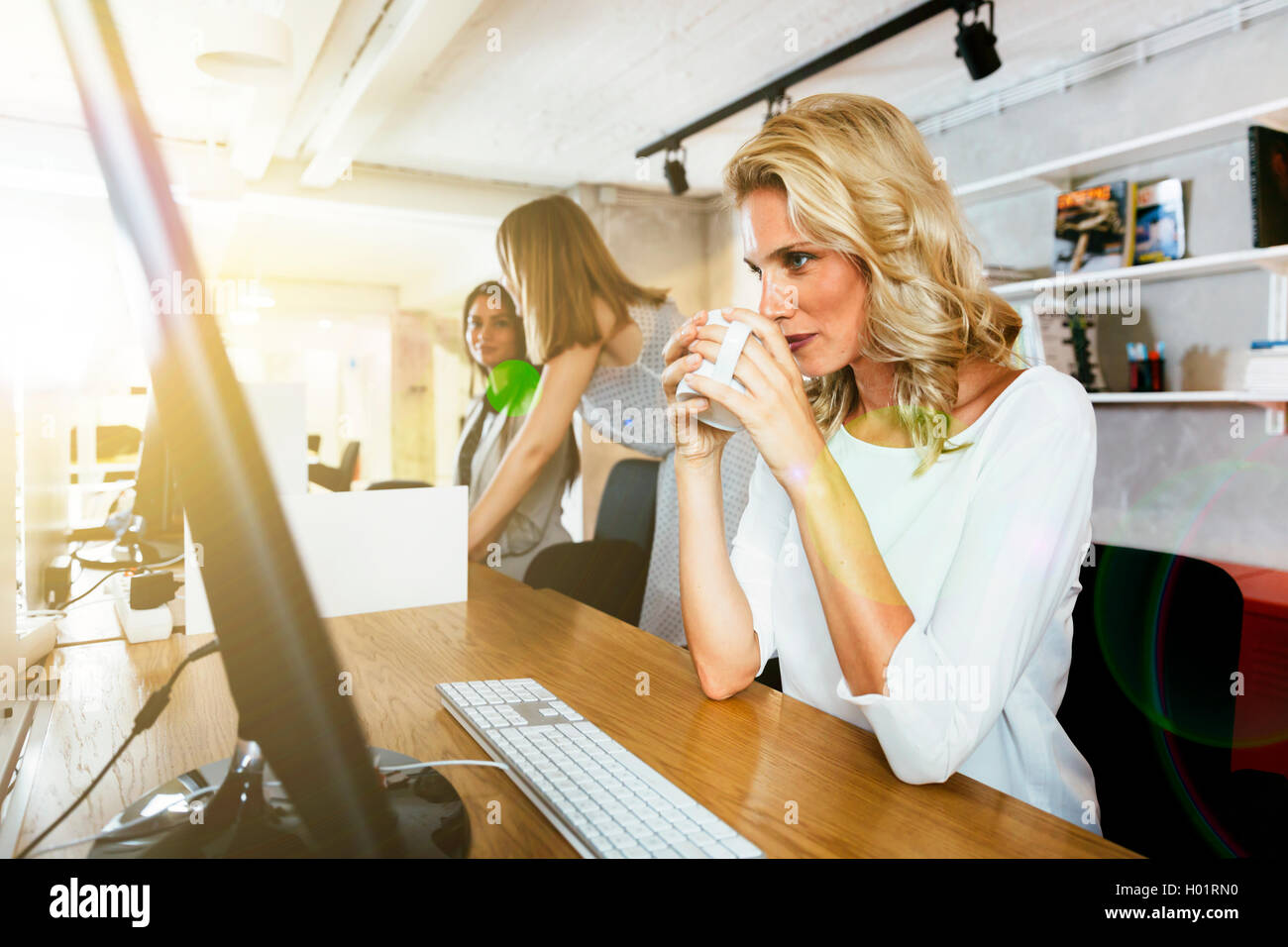 Bella imprenditrice di bere il caffè a rimanere vigili ed essere focalizzati sul lavoro Foto Stock