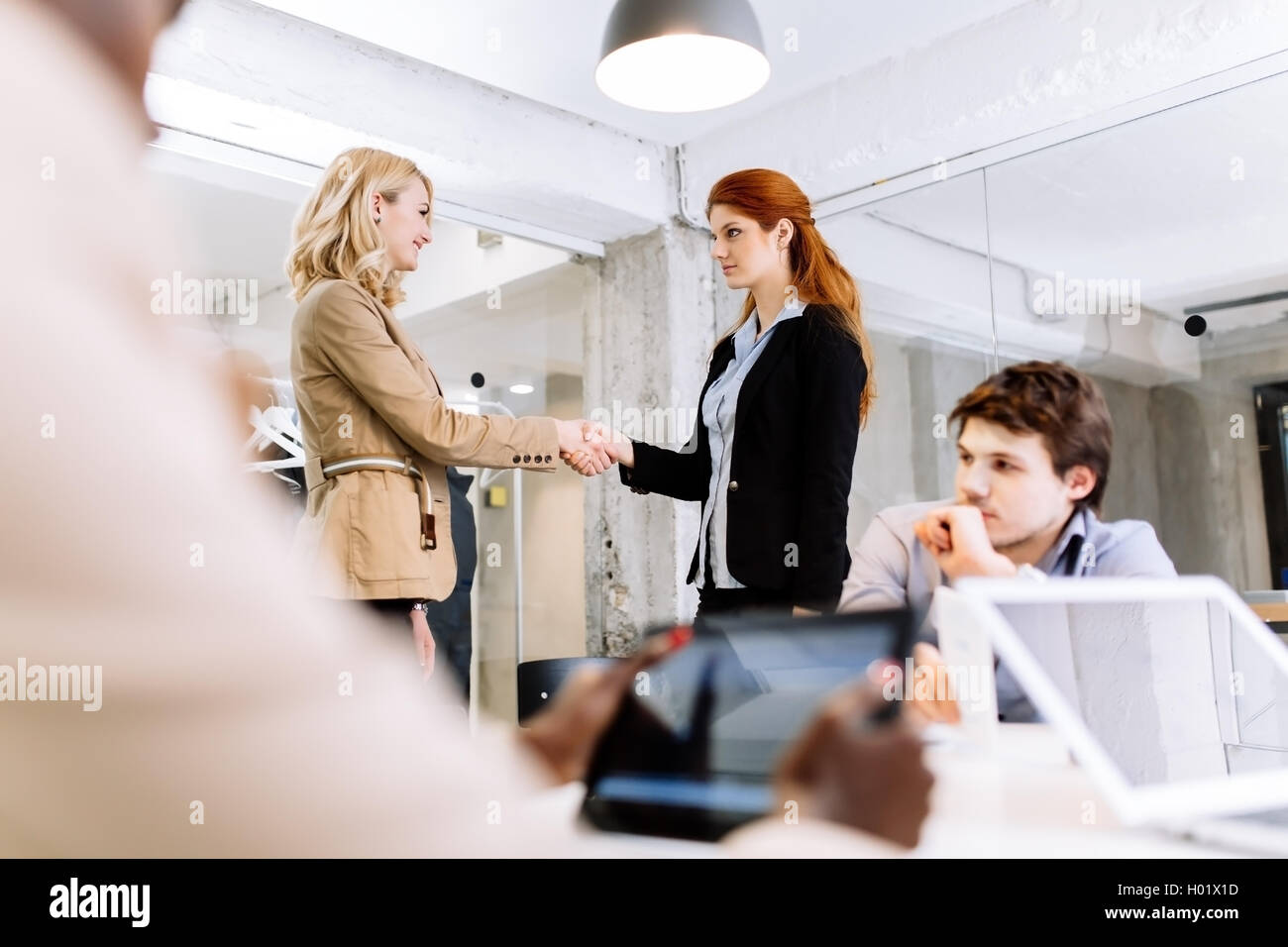 La gente di affari si stringono la mano in ufficio e utilizzando la tecnologia Foto Stock
