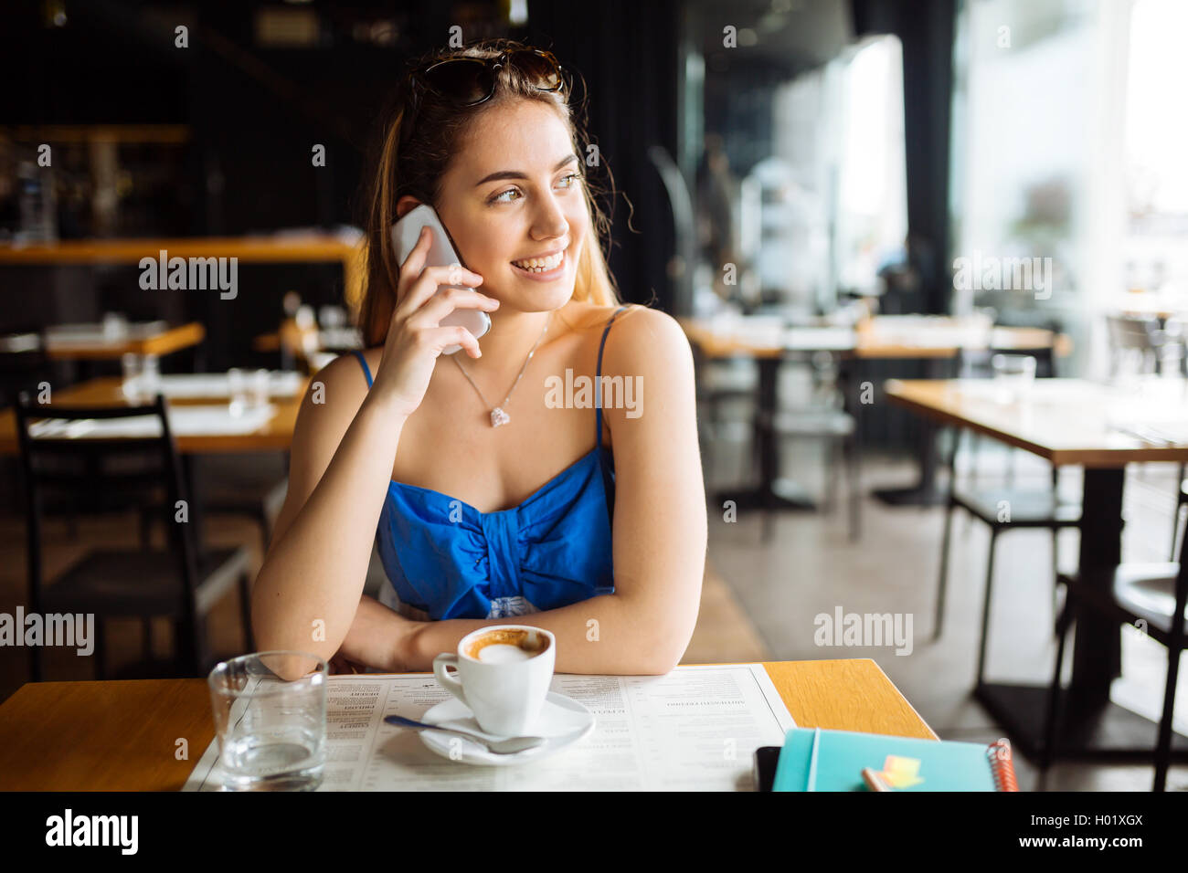 Bella donna parlando al cellulare e di bere il caffè Foto Stock