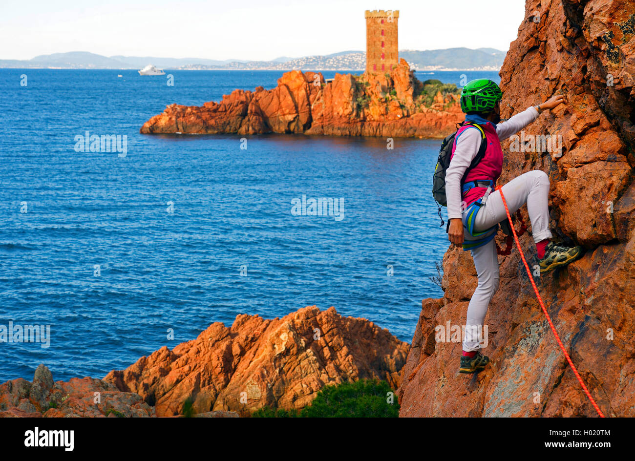 Scalatore alla costa rocciosa di Esterel Massif, torre su ╬le dAEOr in background, Francia, Cotes D. Azur, Esterel Mountain Range, Saint-RaphaÙl Foto Stock