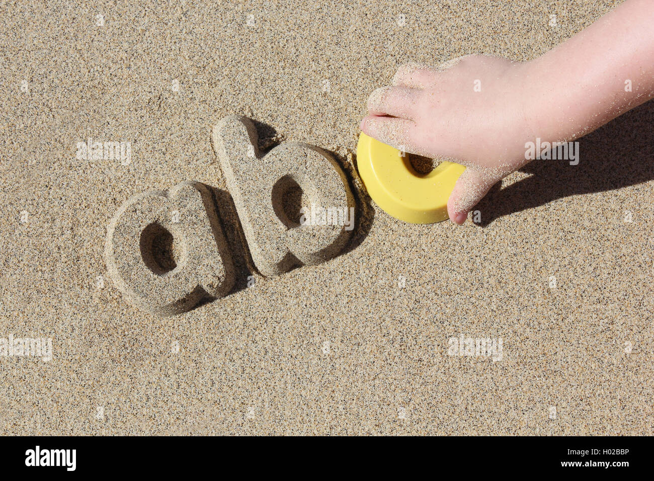 Un bambino che gioca sulla spiaggia. Il bambino ha fatto le lettere 'ABC' in una fila. L apprendimento è divertente. Foto Stock