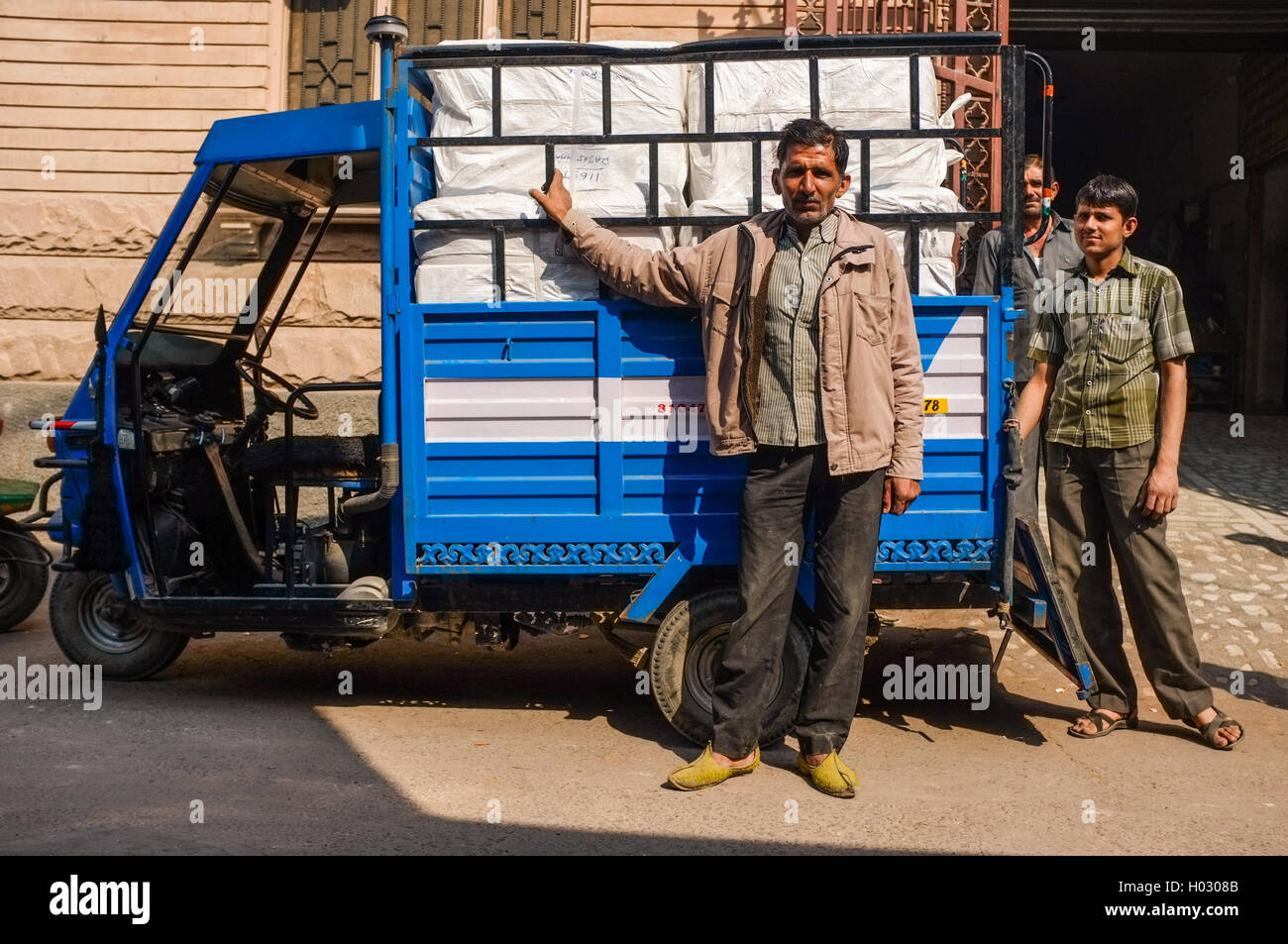 JODHPUR, India - 10 febbraio 2015: Uomini accanto alla consegna a tre ruote con il carico sul retro. Foto Stock