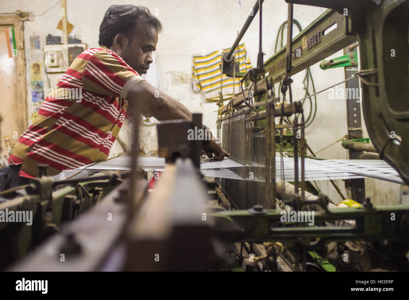 VARANASI, India - 21 febbraio 2015: lavoratore le riparazioni della macchina tessile in fabbrica piccola. Foto Stock