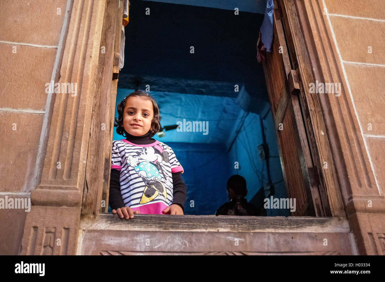 JODHPUR, India - 07 febbraio 2015: Bambina Minnie Mouse shirt guardando attraverso la finestrella in Blu-camera dipinta. Scena comune o Foto Stock