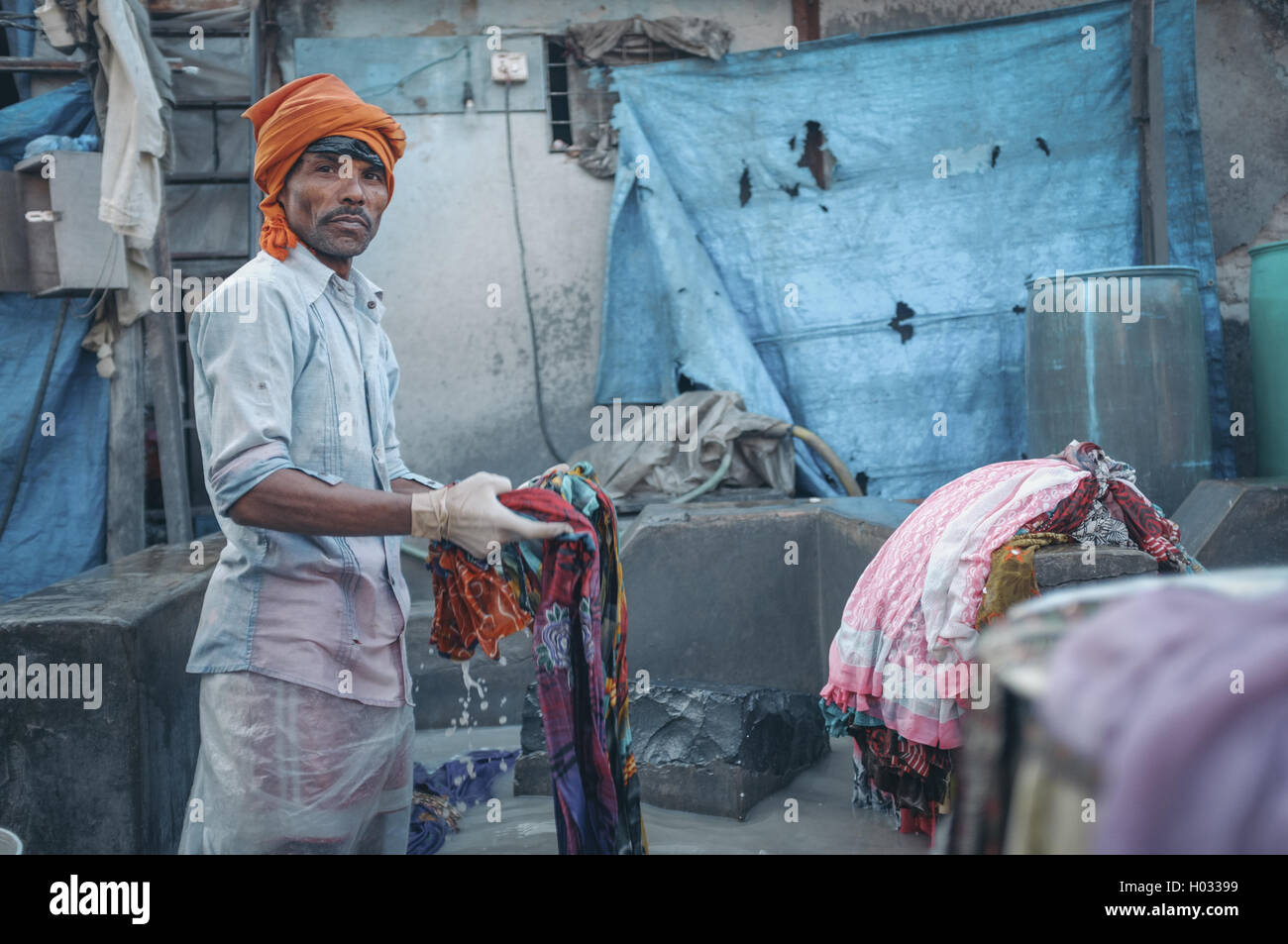 MUMBAI, India - 10 gennaio 2015: lavoratore indiano di lavaggio di un sari in Dhobi ghat. Post-elaborati con grano, di consistenza e di colore effec Foto Stock