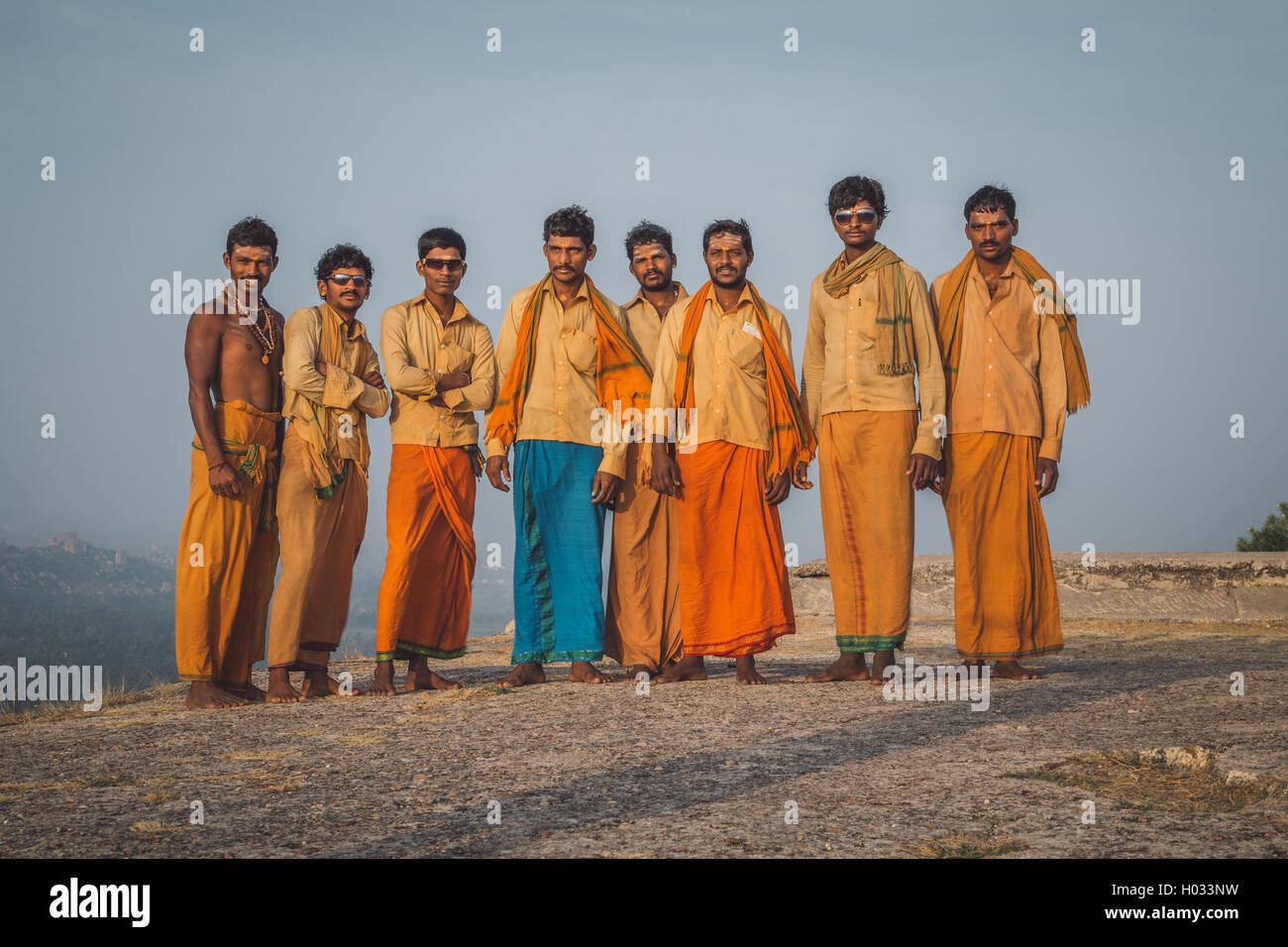 HAMPI, India - 03 febbraio 2015: Otto pellegrini si riuniscono per una foto sulla collina del vestito in abiti di colore arancione. Post-elaborati con gra Foto Stock