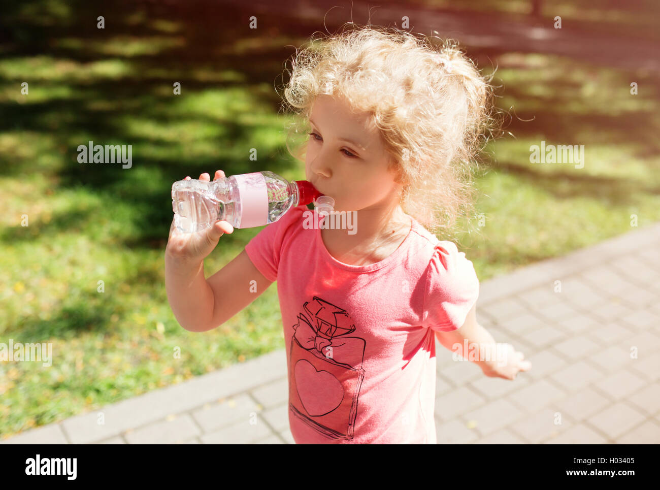 Bambina con una bottiglia di acqua minerale, esterna di estate Foto Stock