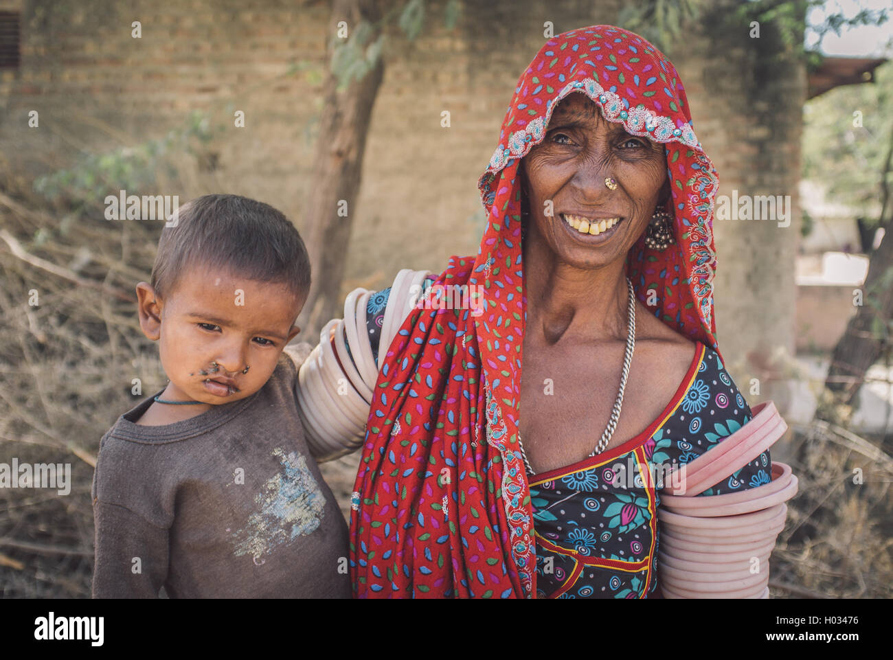 Regione GODWAR, India - 15 febbraio 2015: Anziani tribeswoman indiano indossa abiti tradizionali decorazioni. Il bambino ha le mosche intorno Foto Stock