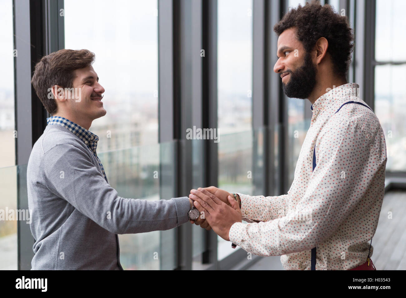 Due giovani imprenditori stringono le mani in un ufficio moderno hall. Foto Stock