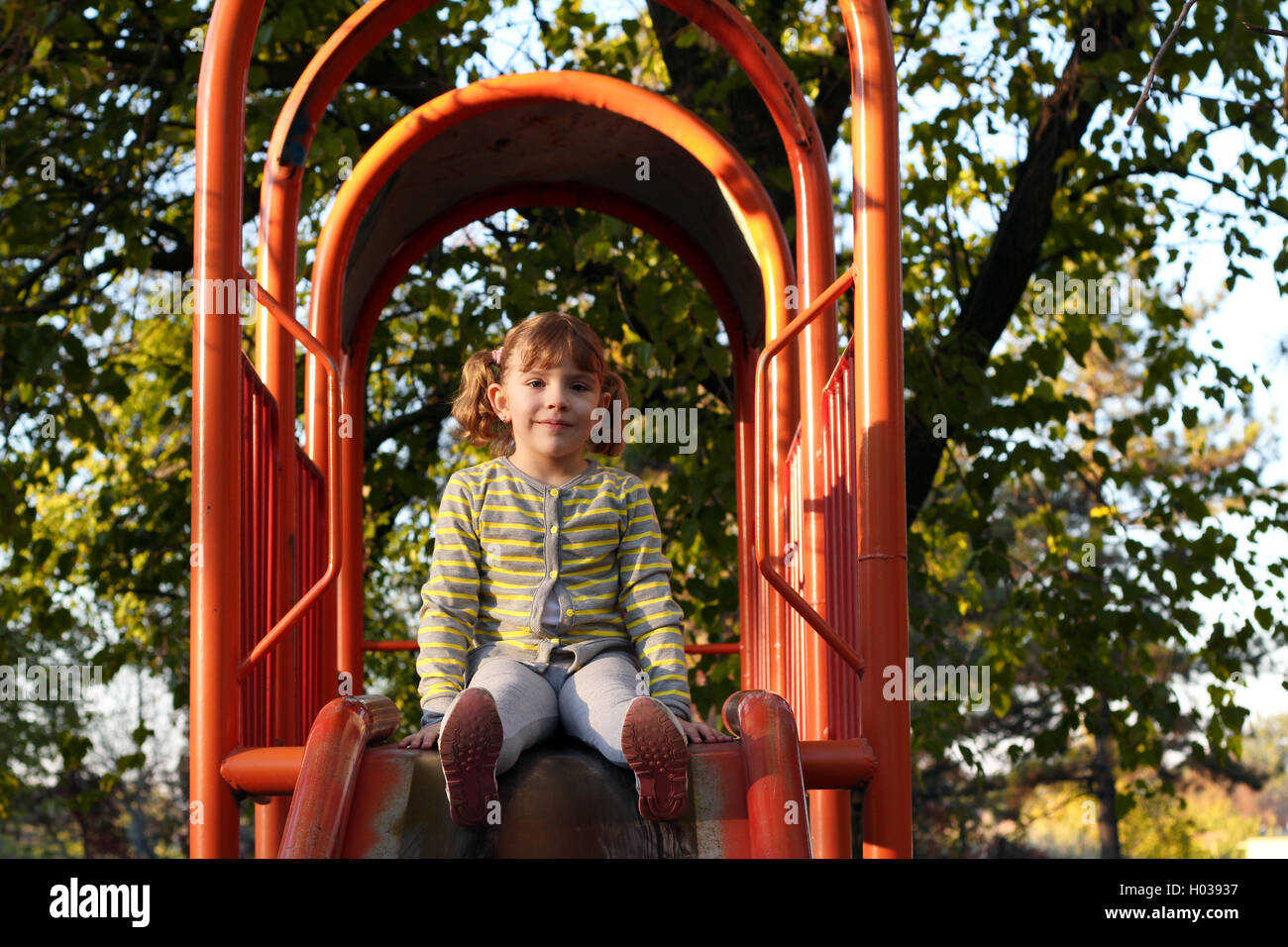 Bella ragazza seduta sul parco giochi slitta Foto Stock