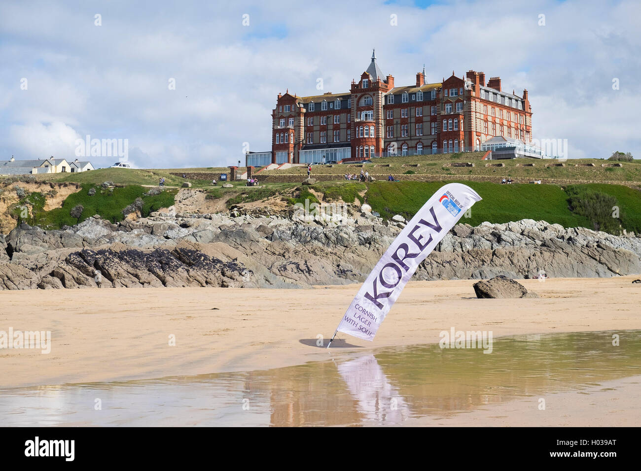 Un Lager Korev banner pubblicitario su Fistral Beach con il Headland Hotel in background. Foto Stock