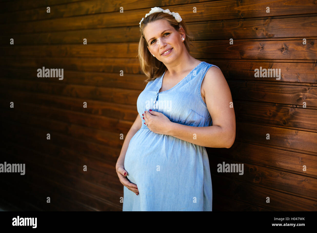 Bella donna incinta mentre tiene il suo ventre Foto Stock