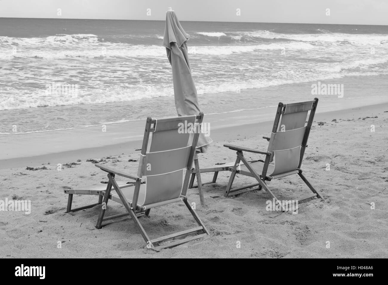 Coppia di spiaggia in legno sedie e ombrellone in Cocoa Beach, Florida. Foto Stock