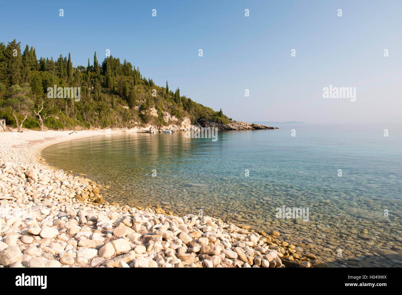 Round pietre e limpido mare sulla società Orkos Beach sulla costa est di Paxos, Isole Ionie, le isole greche - Grecia, Europa Foto Stock