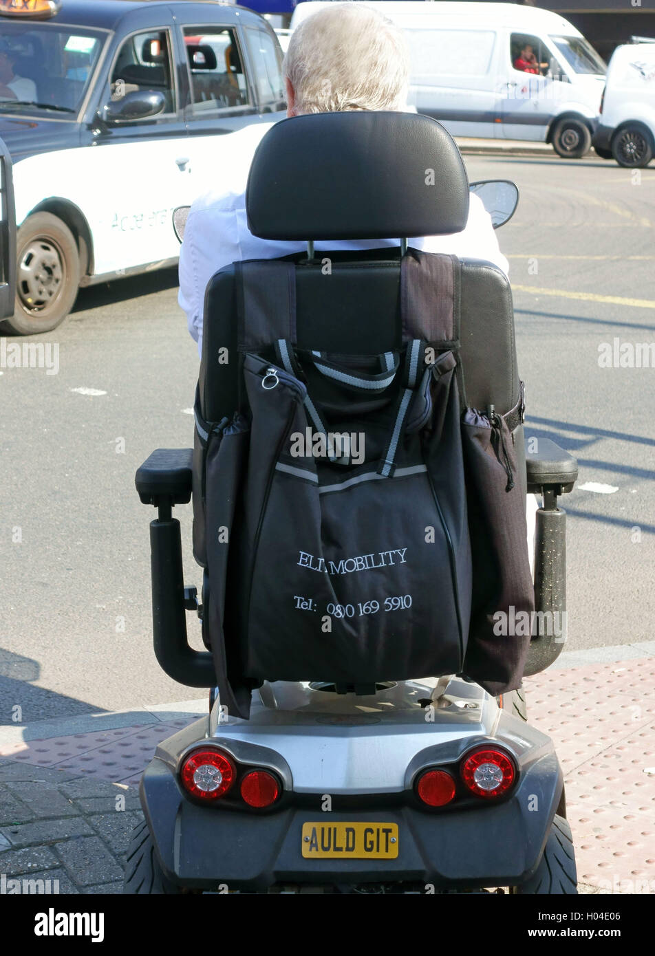 Titolare di pensione o di rendita sulla mobilità scooter con "Auld Git " segno in attesa di Cross Road, Londra Foto Stock