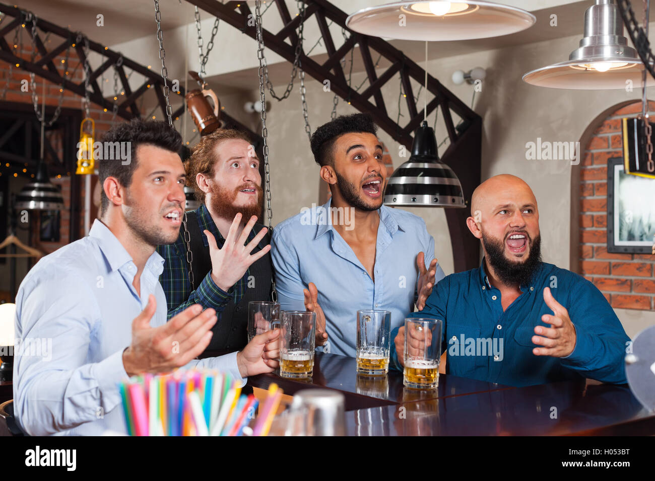 Man Group in bar a bere birra, Mix gara frustrato amici urlando e guardare il calcio Foto Stock