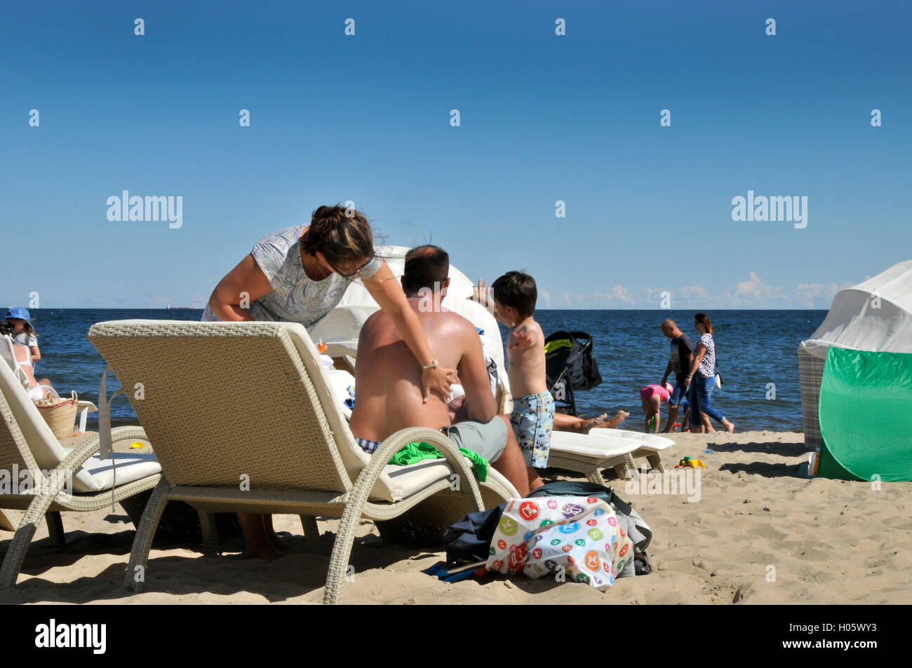Donna applicazione sun tan lotion per mariti indietro Foto Stock