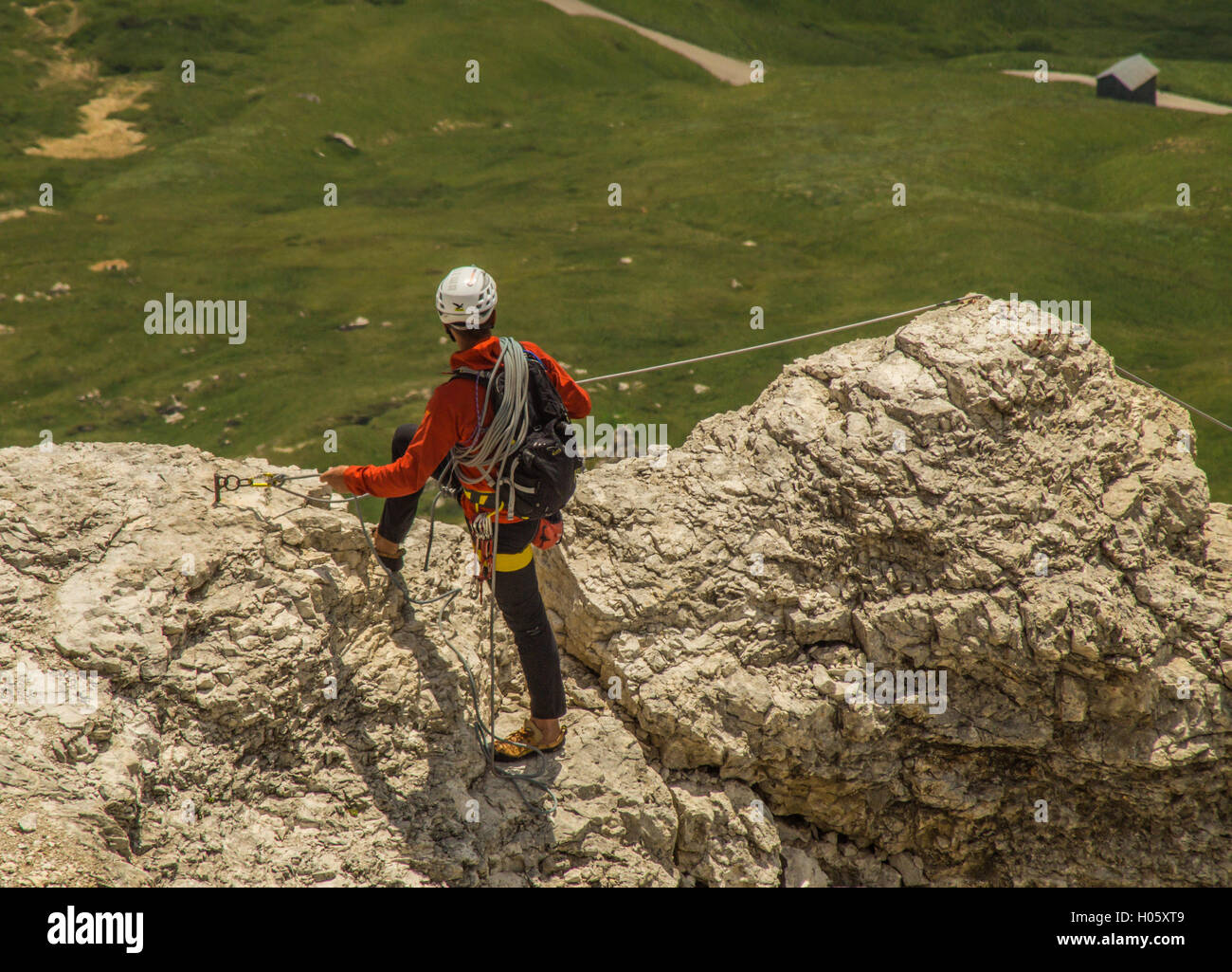Un scalatore di pietra lo guarda giù dopo la sua scalata vicino al Lago di Garda con le sue corde sicuro. Foto Stock