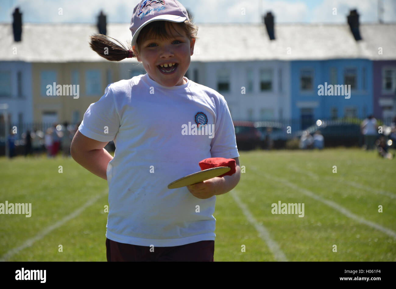 Portrush , Irlanda del Nord - Giugno 12th, 2013 :- la giornata dello sport una giovane donna bambino corre lungo una traccia il bilanciamento di un bean bag su una paletta di legno Foto Stock